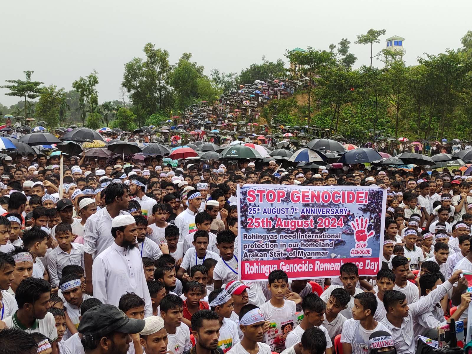 Rohingya refugees in Bangladesh hold a banner at an protest held to mark Rohingya Genocide Day, August 2024 (Mohammed Zonaid / Myanmar Now)